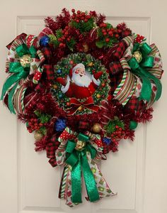 a christmas wreath hanging on the front door with santa clause and evergreens around it