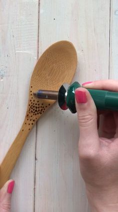 a woman is holding a wooden spoon with a green handle and an empty bottle in front of it