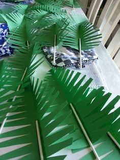 some green paper palm trees are on the table and one is cut out to look like leaves