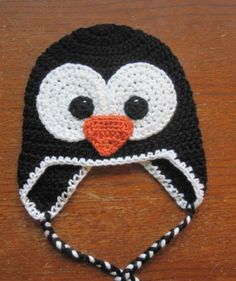 a crocheted penguin hat on a wooden table