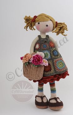 a crocheted doll holding a basket with flowers