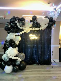 an arch made out of black and white balloons is displayed in front of a backdrop