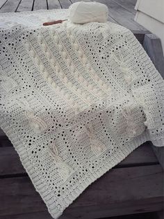 a white crocheted blanket sitting on top of a wooden bench