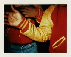 a man in a red and yellow jacket is holding his hand up to the camera