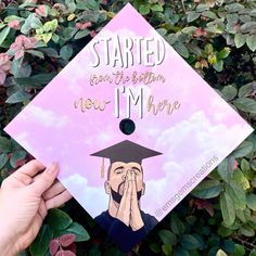 someone is holding their graduation cap in front of some plants and bushes with the words, started from the bottom i'm here