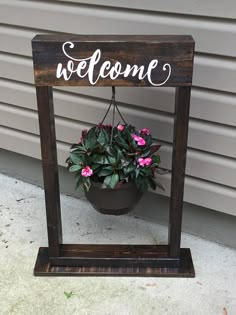 a potted plant sitting on top of a wooden sign with the word welcome above it