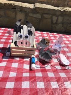 a red and white checkered table cloth with some glasses on it, including two cows