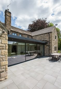 an outdoor patio with tables and chairs next to a stone building on a sunny day