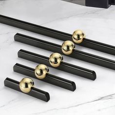 four black and gold door handles on a marble surface