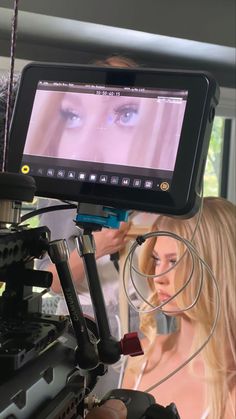 a woman with long blonde hair is looking at an image on the screen while another person stands behind her