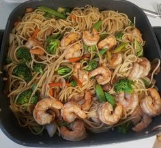 a pan filled with shrimp, broccoli and noodles