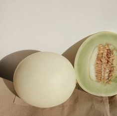 an open melon sitting on top of a brown paper bag next to another piece of fruit