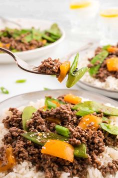 a plate with rice, meat and vegetables on it is being lifted by a fork