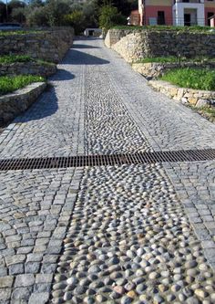 a cobblestone road with an iron grate in the middle on one side