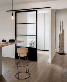 a modern kitchen with wooden floors and white walls, along with black framed glass doors