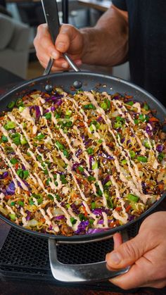 a person holding a skillet filled with food