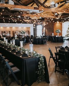 the tables are set up with black linens and greenery for an elegant reception