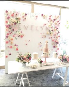 a table with cakes and flowers on it in front of a sign that says evelyn