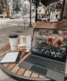 an open laptop computer sitting on top of a wooden table next to a cup of coffee