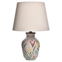 a white lamp with flowers painted on it and a beige shade over the light bulb