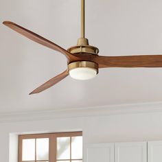 a ceiling fan in a room with white walls and wood trimmings on the ceiling