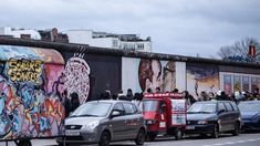 several cars parked in front of a wall with graffiti on it