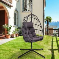 a swing chair sitting on top of a green lawn next to a house and palm trees