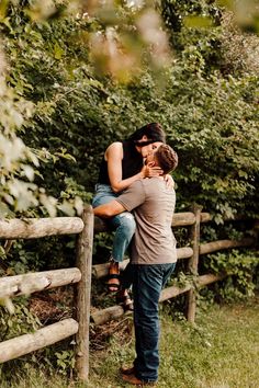 a man and woman leaning on a wooden fence