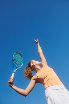 a woman holding a tennis racquet up in the air