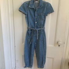 Zara Jumpsuit With Elastic On Back Of Waist, Button Front, Pockets And Tie At Waist. Blue Cotton Button-up Denim Jumpsuit, Casual Blue Overalls With Buttons, Blue Short Sleeve Denim Jumpsuit With Button Closure, Blue Denim Jumpsuit With Short Sleeves And Button Closure, Casual Zara Jumpsuits And Rompers With Pockets, Casual Zara Overalls With Pockets, Trendy Blue Zara Overalls, Casual Medium Wash Jumpsuits And Rompers By Zara, Casual Cotton Jumpsuits And Rompers By Zara