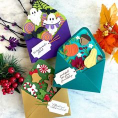 three envelopes decorated with halloween greeting cards and fall leaves on a marble table top