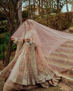 a woman in a wedding dress with a veil over her head and shoes on the ground