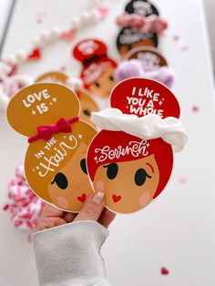 a person holding up some stickers in front of hearts and confetti on the table