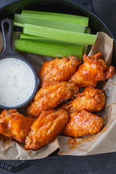 chicken wings and celery sticks with ranch dressing in a cast iron skillet