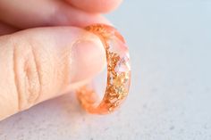 This peach resin ring contains metallic gold flakes suspended in liquid resin. You can wear only one or you can stack two or three rings on a finger.  Width: between 5.5 mm We suggest that you order half a size up from your usual ring size when purchasing a wide band. Wide bands do not leave the tell-tale 'ring mark' on your finger when you take it off, thanks to their greater width. Handmade by me from scratch, each one of my pieces is hand pigmented, and poured into a silicone mold. After I remove it from the mold I hand sand it for you to have a smooth and comfortable piece to wear. Please keep in mind that each piece of jewelry is handmade by me and will be unique in its own way!  Materials: *metallic gold flakes  *resin *pigment Please take into consideration that on some computer mon Peach Resin, Ring Resin, Liquid Resin, Ring Minimal, Edgy Jewelry, Three Rings, Minimalist Gifts, Resin Ring, Gold Flakes