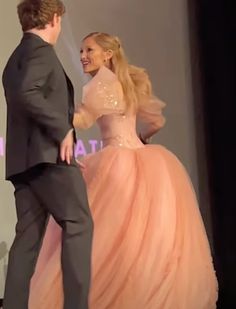 a man in a tuxedo standing next to a woman in a pink dress