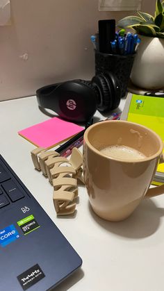 a laptop computer sitting on top of a white desk next to a cup of coffee