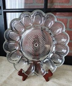 a glass dish with red handles on a table next to a brick wall and window