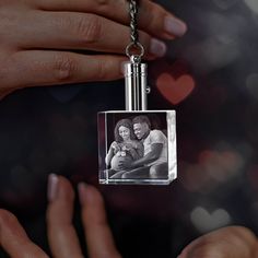 a woman holding a baby in her arms while wearing a necklace with an image on it