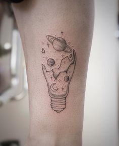 a tattoo on the leg of a woman with an image of planets and a light bulb