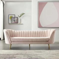 a living room with a pink couch and art on the wall