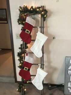 christmas stockings hanging from a ladder with lights on them and santa's stocking