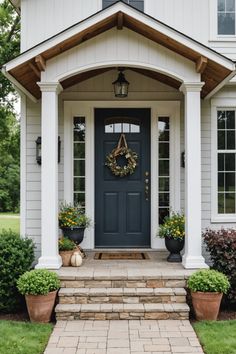 a blue front door with two planters on the steps