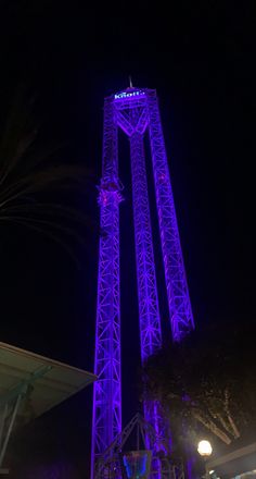 the tall tower is lit up with purple lights