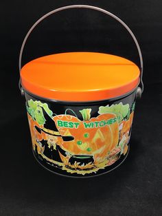 an orange and black bucket with the words best witches on it is sitting in front of a black background