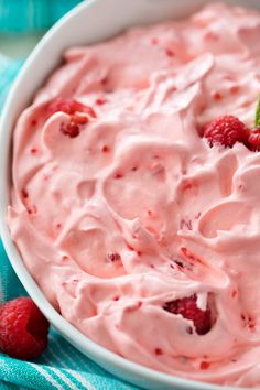 a close up of a bowl of food with raspberries on the side and strawberries in the middle