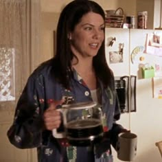 a woman holding a coffee pot in her kitchen