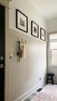 a room with white walls and pictures hanging on the wall, along with a pink rug