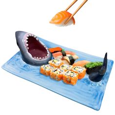 a plate with sushi, chopsticks and an open shark's mouth