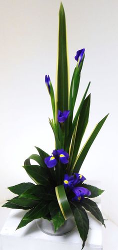 a vase with purple flowers and green leaves